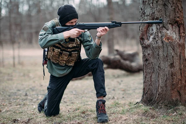 若い男は練習し 森の中でボディアーマーとバラクラバで身に着けていたポンプ銃から目的 — ストック写真