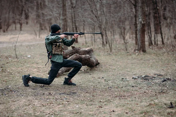 若い男は練習し 森の中でボディアーマーとバラクラバで身に着けていたポンプ銃から目的 — ストック写真