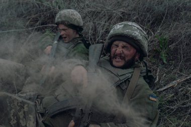 Rus düşmanlarının topçu bombardımanı sırasında iki Ukraynalı asker, Kalaşnikof 'la birlikte kuru çimlere saldırıyor. Ukrayna 'da Rus askeri istilası kavramı. Ukrayna ve Avrupa 'da savaş.