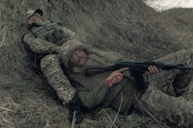 Rus düşmanlarının topçu bombardımanı sırasında iki Ukraynalı asker, Kalaşnikof 'la birlikte kuru çimlere saldırıyor. Ukrayna 'da Rus askeri istilası kavramı. Ukrayna ve Avrupa 'da savaş.