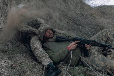 Rus düşmanlarının topçu bombardımanı sırasında iki Ukraynalı asker, Kalaşnikof 'la birlikte kuru çimlere saldırıyor. Ukrayna 'da Rus askeri istilası kavramı. Ukrayna ve Avrupa 'da savaş.