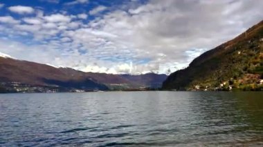 Göl kıyısı, gökyüzü, bulutlar ve karla kaplı Alp dağlarının tepelerine karşı..