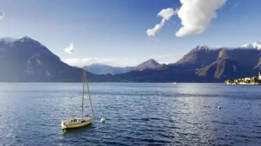 Gökyüzü, bulutlar ve karla kaplı Alp dağlarının zirvelerinde yüzen yatı olan Como Gölü.