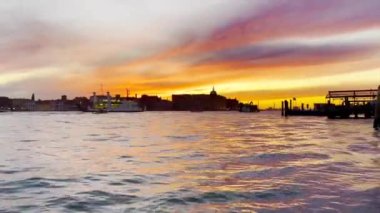 Venedik 'te manzaralı gökyüzüne karşı gemi ve sürat tekneleriyle güzel gün batımı manzarası.