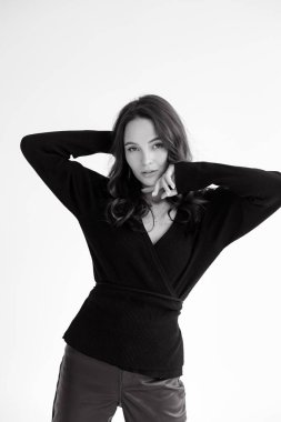 Young slim brunette woman in pants and shirt poses against white background. White background isolated image. Black and white image.