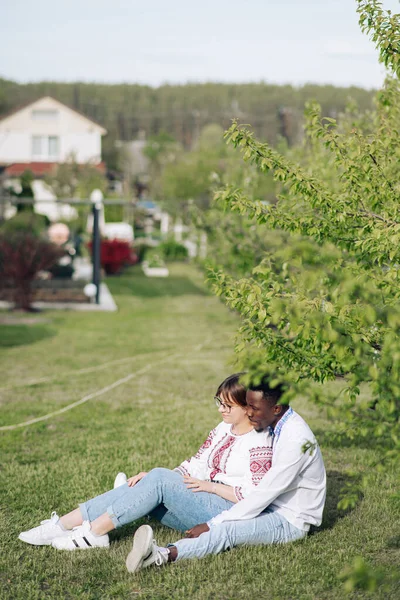 Pareja Interracial Sienta Hierba Jardín Primavera Vestido Con Camisas Bordadas — Foto de Stock