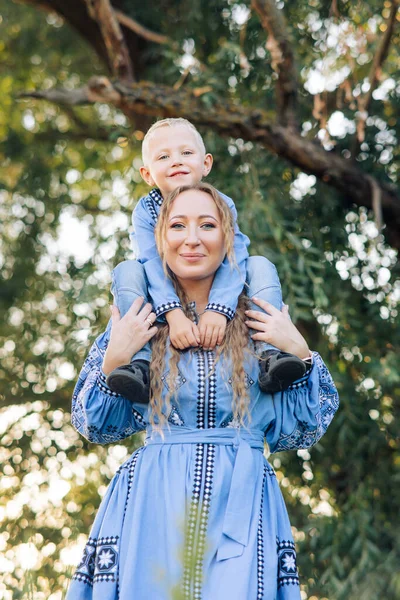 Happy Mother Carries Her Son Her Shoulders Walk Park Dressed — стоковое фото