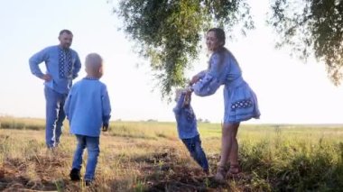 Mutlu anne oğluyla oynar ve yürürken ellerini tutarak döner. Bütün aile parkta. Ukrayna ulusal nakışlı gömlekler giyiyorlar..