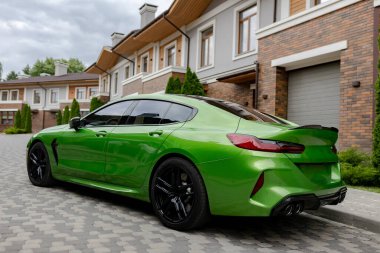 Modern green car is on parking near garage gate of beautiful house.