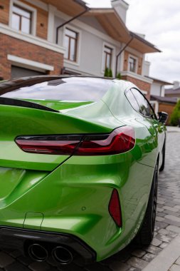 Closeup view to brake light and turn indicator of modern green car standing near house.
