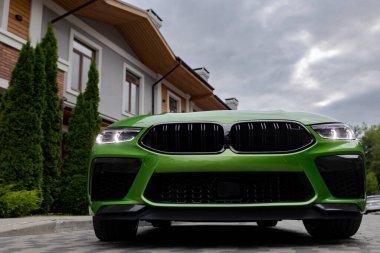 Modern green car is on parking near beautiful house with landscaping. Bottom view.