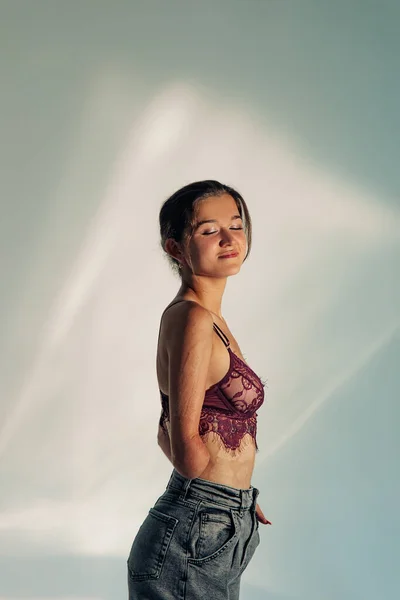Smiling young woman with amputee arm and scars from burn on her body poses in lacy bra. The concept of a fulfilling life of persons with disabilities.