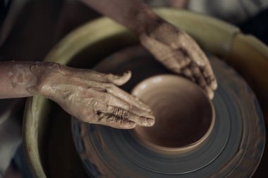 Hands of potter sculpt handmade earthenware on spinning pottery wheel in workshop closeup. Top view.