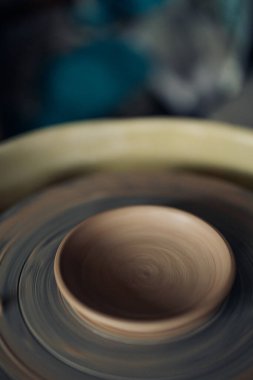 Handmade earthenware saucer on pottery wheel in workshop closeup.