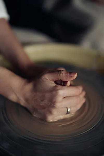 Hands of potter sculpt handmade earthenware on spinning pottery wheel in workshop closeup.