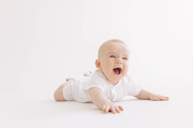 Mutlu erkek çocuk beyaz arka planda yalan söyleyerek güler..