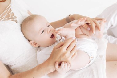 Anne oturur ve beyaz arka planda bebeğiyle oynar. Yakın çekim..