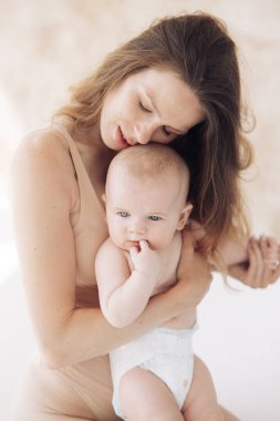 Genç ve mutlu bir anne oturuyor ve bebeğini kucaklıyor. Yakın çekim..