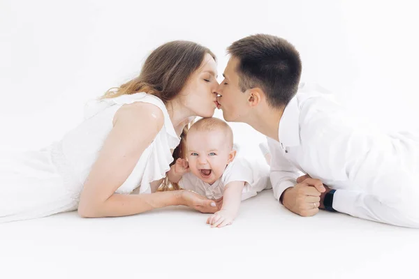 Mladí Šťastní Rodiče Lžou Líbají Vedle Svého Smějícího Syna Bílém — Stock fotografie