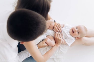 Genç mutlu ebeveynler beyaz arka planda oturup küçük çocuklarıyla oynarlar. Üst görünüm.