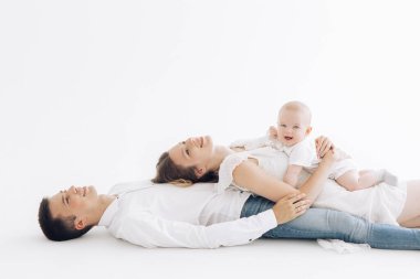 Erkek çocuklu mutlu bir aile yalan söylüyor ve beyaz arka plana karşı birbirlerini kucaklıyorlar..