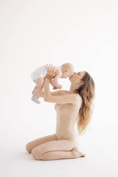 Νεαρή Μητέρα Κοστούμι Κάθεται Και Φιλάει Μωρό Της Λευκό Φόντο — Φωτογραφία Αρχείου