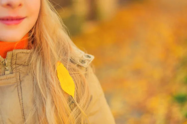 Close-up van een geel herfstblad dat op het blonde lange haar van een kleuter viel. Foto met plaats voor tekst — Stockfoto