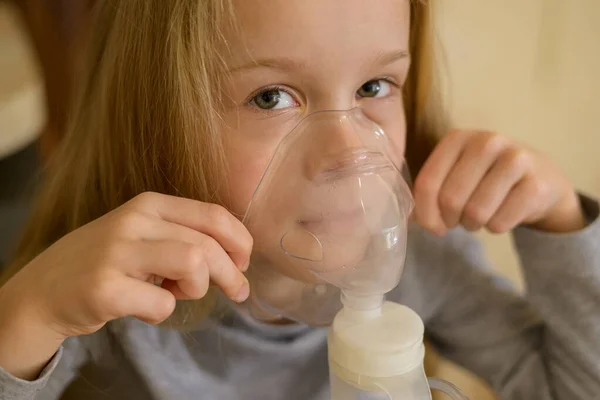 Uma criança doente faz inalação com um nebulizador em casa: ele mantém uma máscara a partir da qual o vapor. A criança não está se sentindo bem. Saúde — Fotografia de Stock