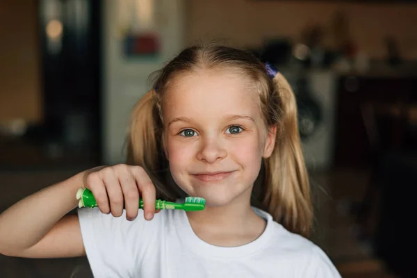 Portret van een kind dat thuis met een glimlach zijn tanden poetst met een groene tandenborstel. Hygiëne en gezondheid preventie van tandaandoeningen en mondholte bij kinderen — Stockfoto