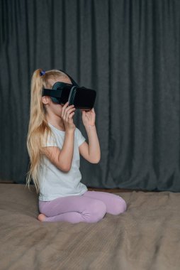 Evde sanal gerçeklik gözlüklü çocuk video izleyip oyun oynuyor. Modern çocuklar teknolojik yenilikler konusunda çok bilgilidirler. Alfa kuşağı. Yüksek kalite fotoğraf