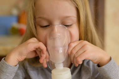 Hasta bir çocuk evde nebulizörle solunum yapar: Buharı olan bir maske tutar. Çocuk kendini iyi hissetmiyor. Sağlığa. Yüksek kalite fotoğraf