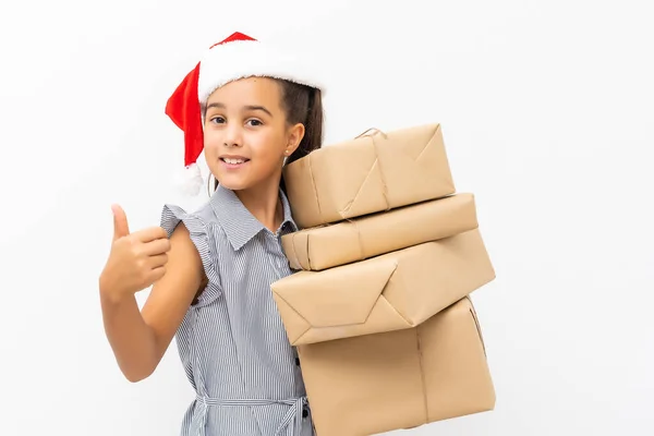 Niño pequeño sosteniendo una gran pila de regalos de Navidad con un sombrero de Santa aislado en blanco —  Fotos de Stock