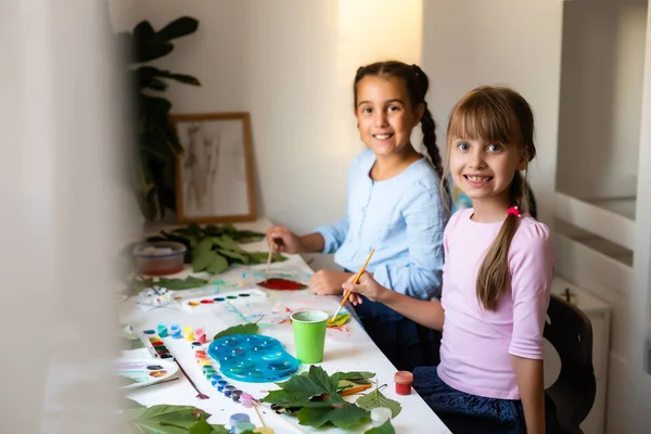 Two schoolgirls paint the leaves — Stock Photo, Image
