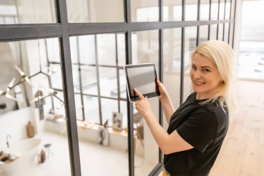 Dijital tablet kullanan gülümseyen genç bir kadın.