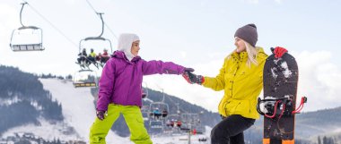 Anne ve kızı kış tatilinde snowboard yapıyor.