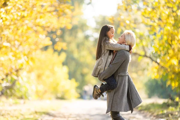 Madre alla moda con figlia. Famiglia in un parco autunnale. Figlia in cappotto. — Foto Stock