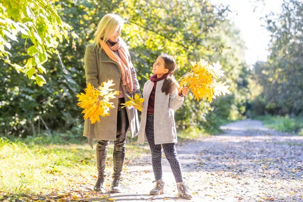 Divatos anya a lányával. Család egy őszi parkban. Kislány kabátban.. — Stock Fotó