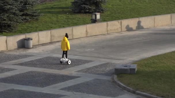 Elektrikli scooter kullanan küçük bir kız. Kişisel çevre taşımacılığı, jiroskoplu scooter, akıllı denge çarkı. Popüler elektrik taşımacılığı — Stok video