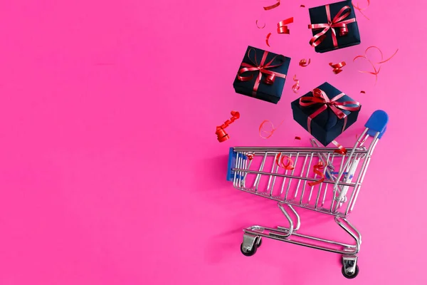 Χριστουγεννιάτικα δώρα και ψώνια σε τρόλεϊ απομονώνονται σε ροζ φόντο. — Φωτογραφία Αρχείου