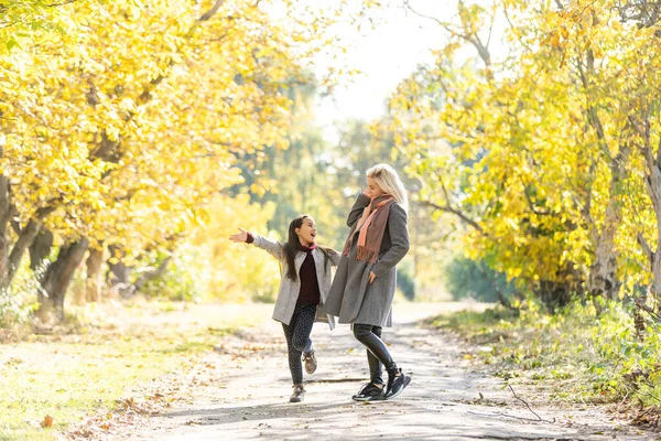 Familia feliz: madre e hija pequeña juegan en otoño caminar en la naturaleza al aire libre — Foto de Stock