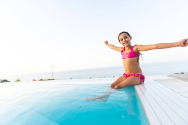 Suya atlama yaz tatile tropikal plaj adada açık yüzme havuzunda oynayan küçük bir kız. Çocuk lüks resort açık havuzda yüzmek için öğrenme.