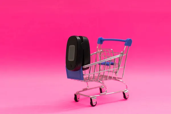 Παλμικό οξύμετρο σε ένα τρόλεϊ σούπερ μάρκετ σε ροζ φόντο — Φωτογραφία Αρχείου