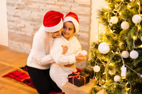 Mutlu Noeller ve mutlu tatiller anne ve kızı odadaki Noel ağacını süslüyor. Aileyi içeride sevmek. — Stok fotoğraf