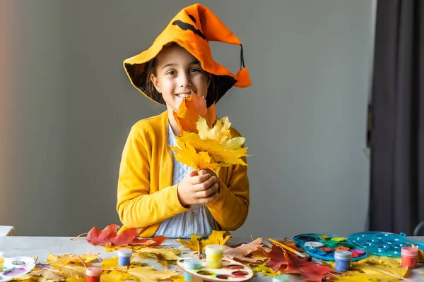 Dívka v kostýmu čarodějnice dělá podzimní dekoraci doma. halloween koncept — Stock fotografie