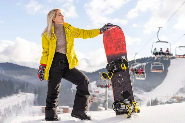 在冬季度假胜地的山坡上架着雪板的年轻女子 — 图库照片