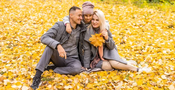 Tânără familie fericită în timp ce merge în parcul de toamnă . — Fotografie, imagine de stoc