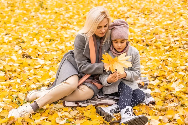 快乐的家庭母亲和孩子的女儿在秋天散步时嬉笑着玩耍。母子关系。时尚的母亲和女儿，穿着同样的外套，看起来很时髦 — 图库照片