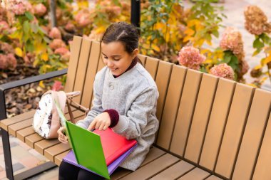 Sırt çantalı küçük okul kızı. Mutlu bir çocukluk. Akademik yılın başlangıcında. Çalışmak için sonbahar zamanı. İlkokulda okuyor. Okul eğitimi konsepti. Çalışmaya devam.