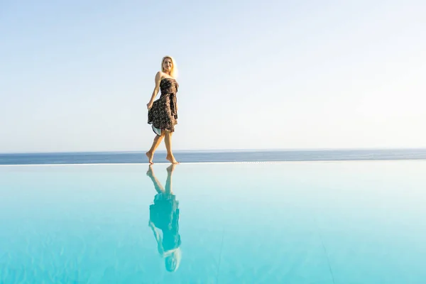 An attractive young woman stands near the pool with a panoramic view. — Stock Photo, Image