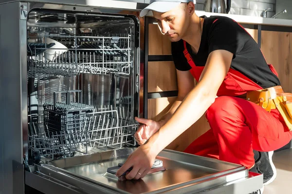 Mladý opravář servisní pracovník opravy myčka nádobí spotřebič v kuchyni — Stock fotografie